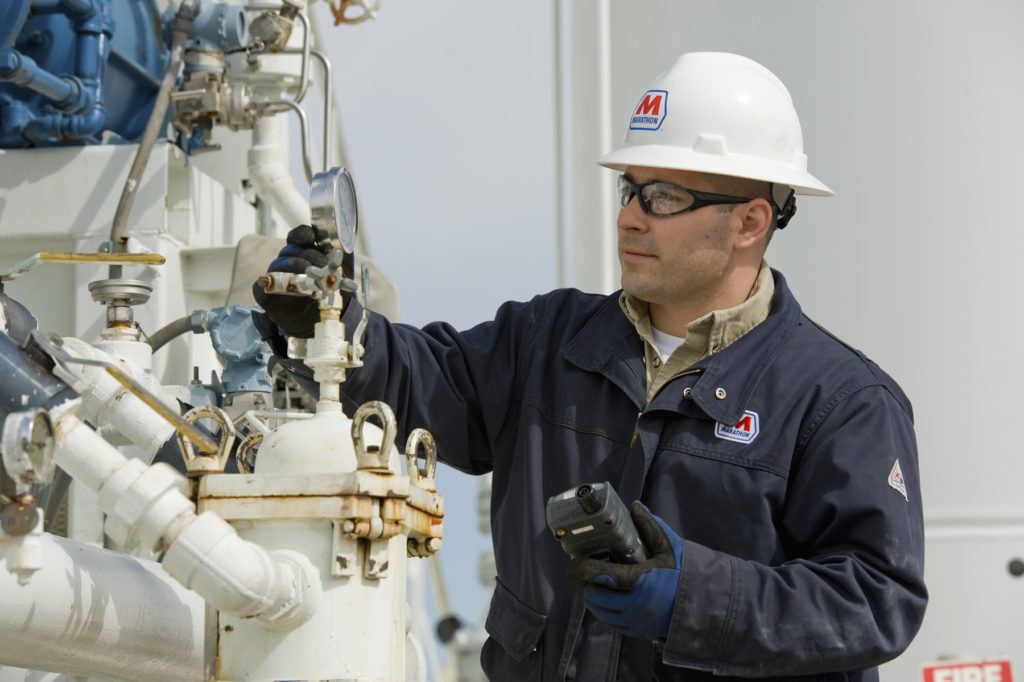Refinery engineer inspecting equipment, valves, and gauges to prevent shutdowns